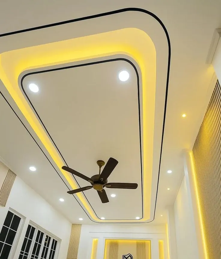 Rounded layered gypsum ceiling with warm cove lighting and a ceiling fan