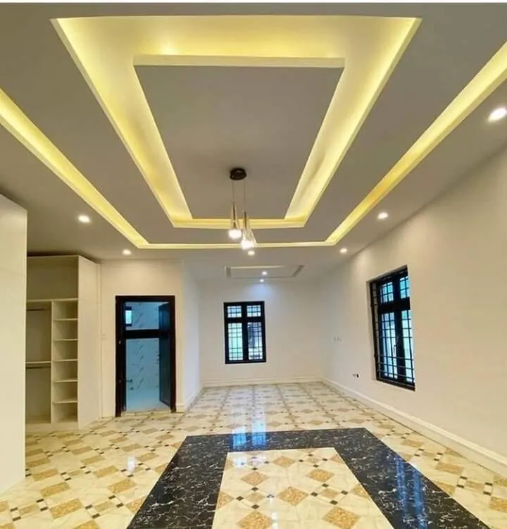 Layered gypsum ceiling with warm cove lighting over a large hall with a patterned floor