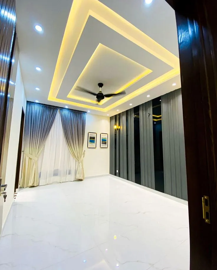 Gypsum ceiling with stepped cove lighting and a ceiling fan in a living room