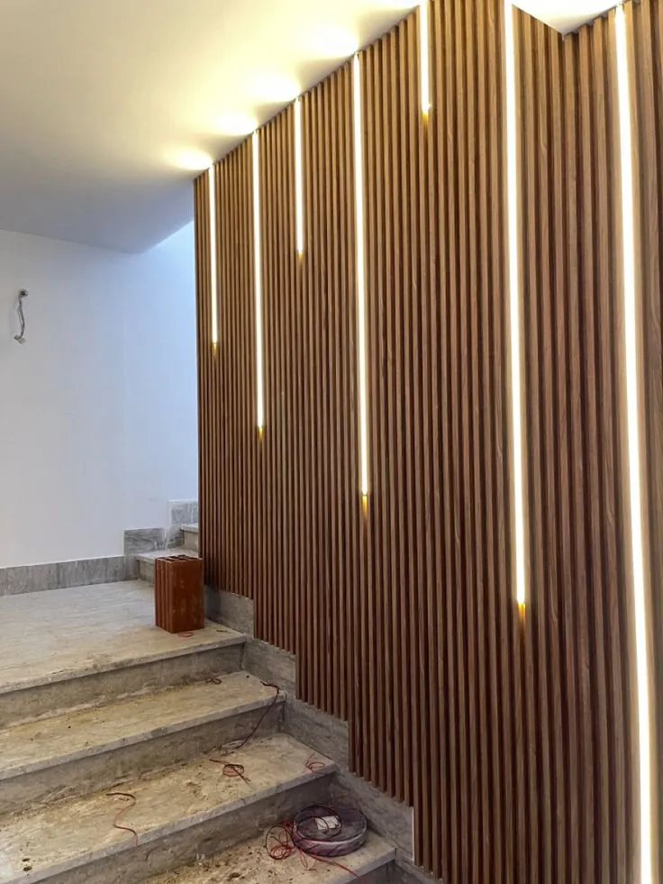 Wood-effect fluted wall panels with vertical LED lights beside a staircase
